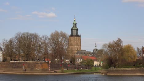 Zeitraffer-Von-Countencance-Stadtbild-Von-Der-Anderen-Seite-Des-Flusses-Ijssel-Der-Historischen-Niederländischen-Mittelalterlichen-Stadt-Zutphen-In-Den-Niederlanden-Mit-Der-Walburgiskerk-kathedrale,-Die-Sich-Vor-Blauem-Himmel-Erhebt