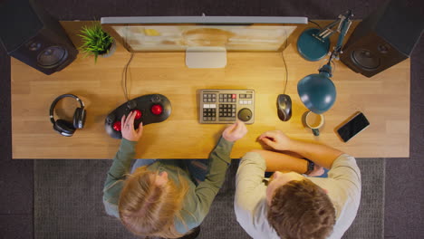 Overhead-View-Of-Male-And-Female-Video-Editor-Working-At-Computer-In-Creative-Office-At-Night