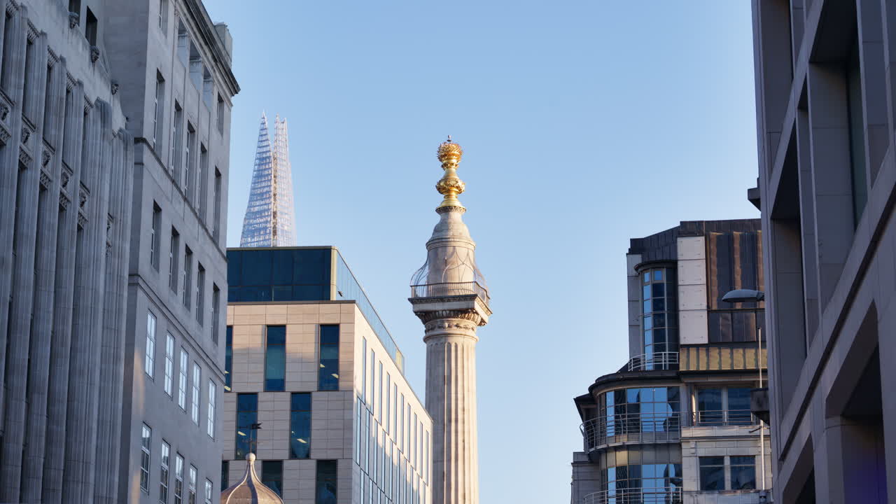 Low-angle view of The Monument to the Great Fire of London with The Shard in the background against a clear sky