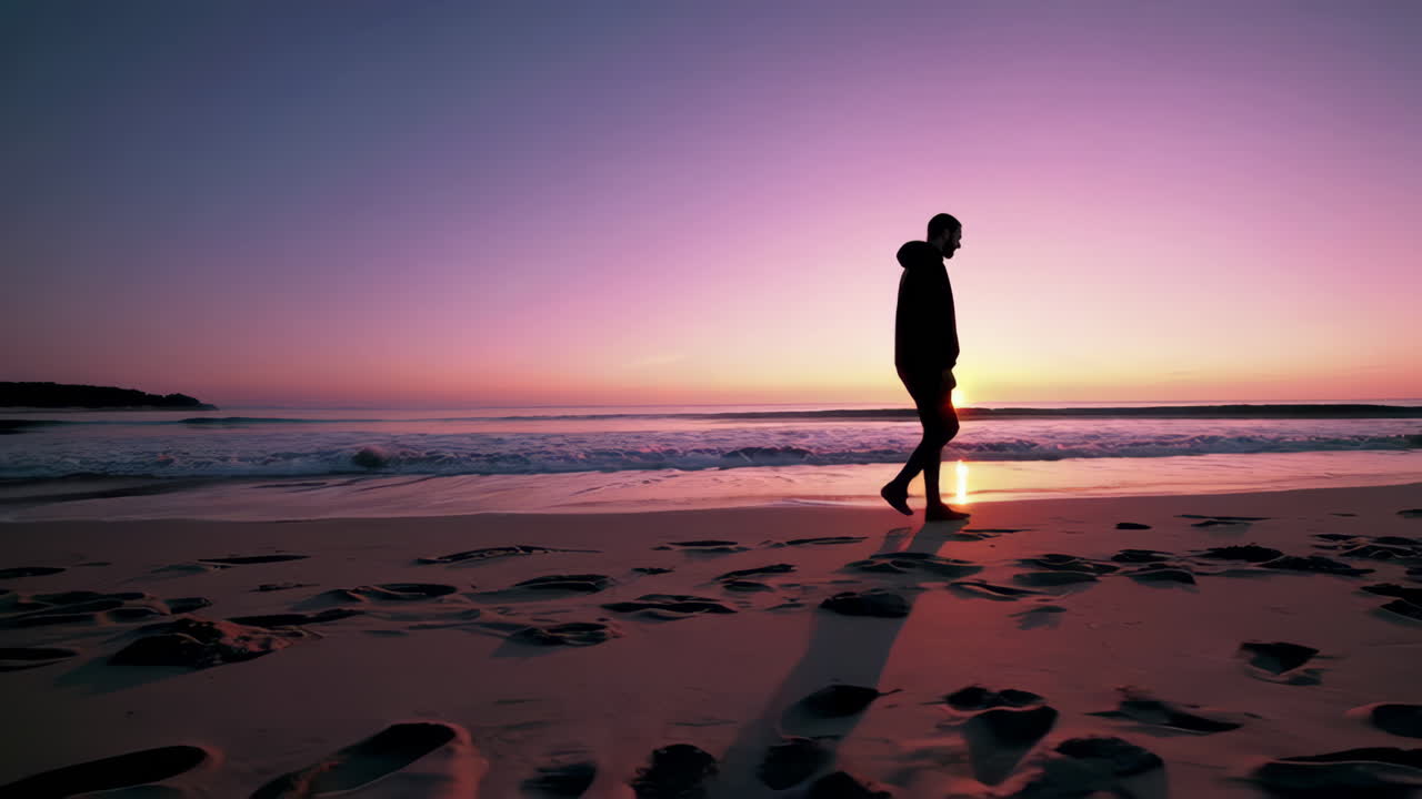 Silhouette of a Person Walking on a Beach at Sunset