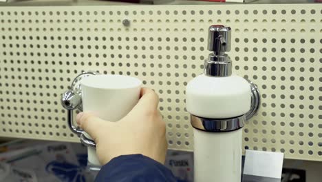 young guy is considering bathroom accessories in a building materials store