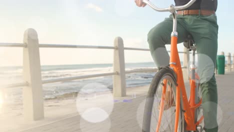 Animation-Von-Lichtflecken-über-Einem-Biracial-Mann-Beim-Radfahren