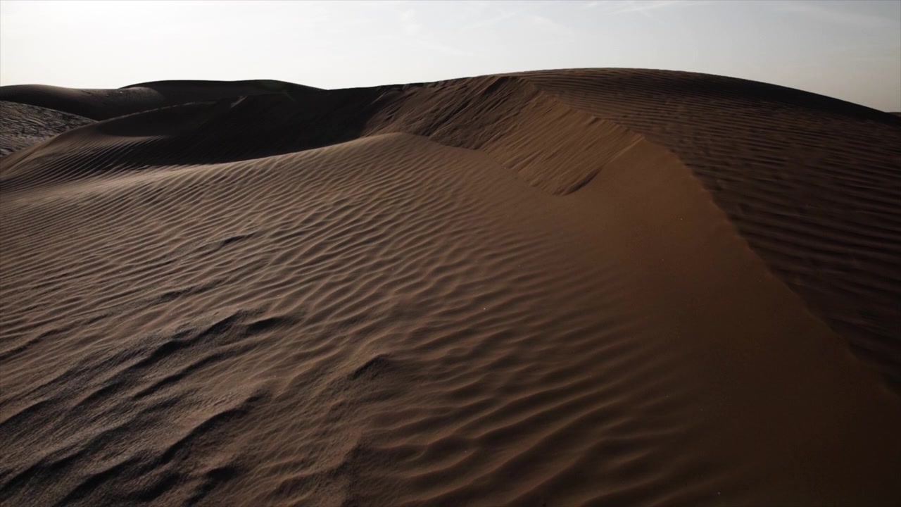 Sabbia che si muove al rallentatore sulle dune di sabbia in un deserto. Paesaggio desertico mediorientale vicino a Dubai negli Emirati Arabi Uniti