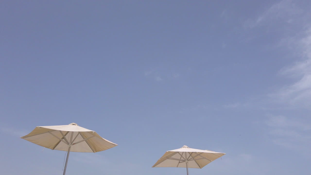 일광욕용 라운저의 기울기 샷 - 푸른 하늘이 있는 화창한 날 고급 수영장 옆에 우산