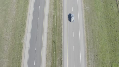 Dolly-Rolle-Aus-Der-Vogelperspektive-Aus-Der-Vogelperspektive-über-Die-Autobahn,-Da-Es-Eine-Grasfeld-Trennwand-Zwischen-2-Fahrspuren-Auf-Jeder-Seite-Gibt,-Die-An-Einem-Sonnigen-Sommertag-Für-Wohnmobil-LKW-Tanker-Hwy1-2-Nach-Osten,-Westen,-Norden-Oder-Süden-Führen