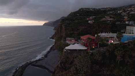 Vista-Aérea-Nocturna-Del-Idílico-Pueblo-Con-Coloridas-Casas-Rojas,-Amanecer-En-Ponta-Do-Sol,-Madeira,-Portugal