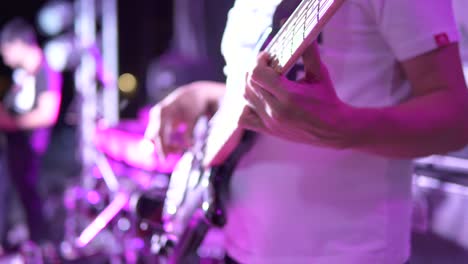 Vista-De-Cerca-De-Las-Manos-Masculinas-Tocando-El-Bajo-Con-Luz-De-Neón-Azul.-Músico-Tocando-El-Bajo-En-Vivo-Durante-El-Concierto-En