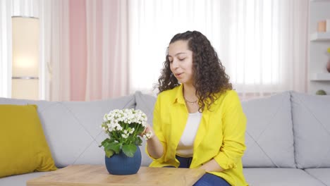 Young-woman-smelling-pot-flower-at-home.