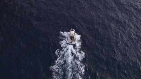 Top-down-shot-of-fishing-boat-cruising-on-rough-ocean-near-Mallorca,-aerial