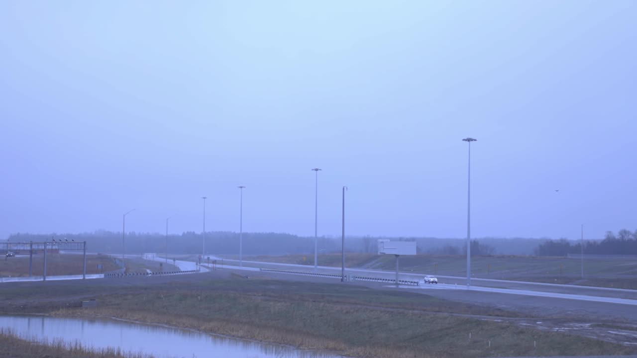 Single Car Traveling On The Highway With Street Lights Early In The Morning- Coronavirus Effects - wide shot