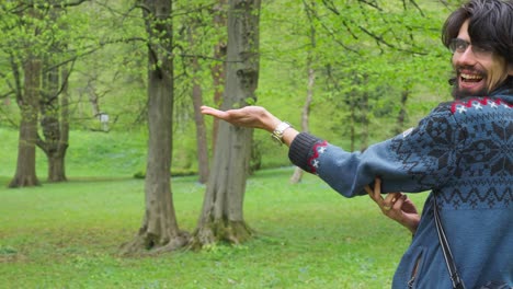 un joven entusiasta alimenta a un pájaro paseriforme de tit azul euroasiático de la mano en el parque