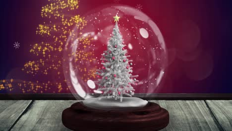 Animation-of-snow-falling-and-glowing-spots-over-snow-globe-with-tree-on-red-background