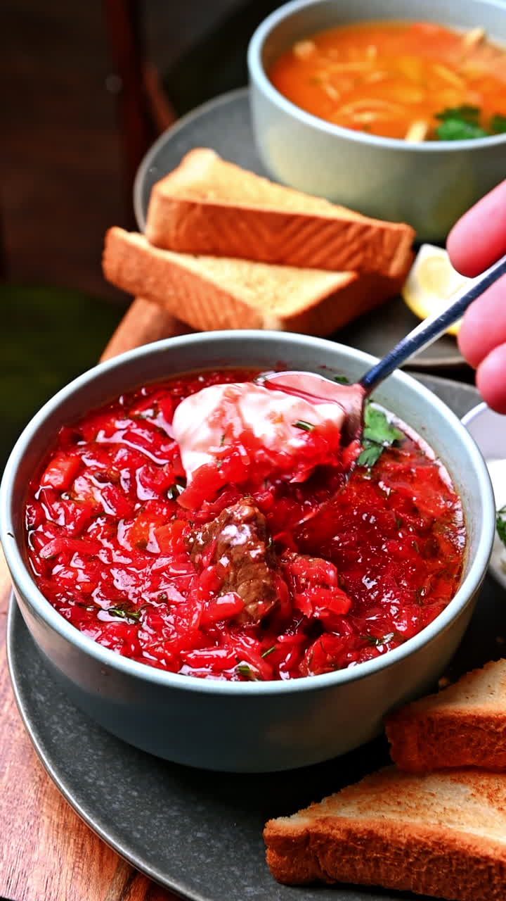 Traditional borscht with sour cream and toast bread. Hot Ukrainian borscht soup with sour cream, herbs, and crispy toast on wooden table