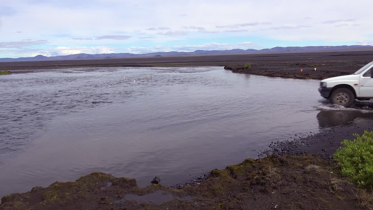낡은 픽업트럭이 아이슬란드의 외딴 고원에서 강을 가로질러 운전한다