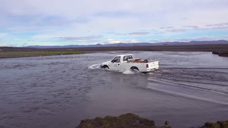 an old pickup truck drives through a river in the remote highlands of iceland