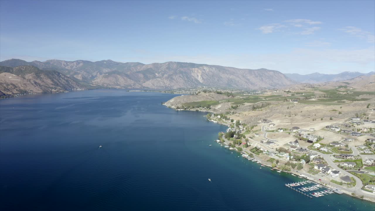 Drone flying over houses towards lake and mountains