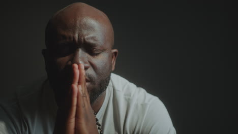 hopeful black man holding hands together and praying to god deeply