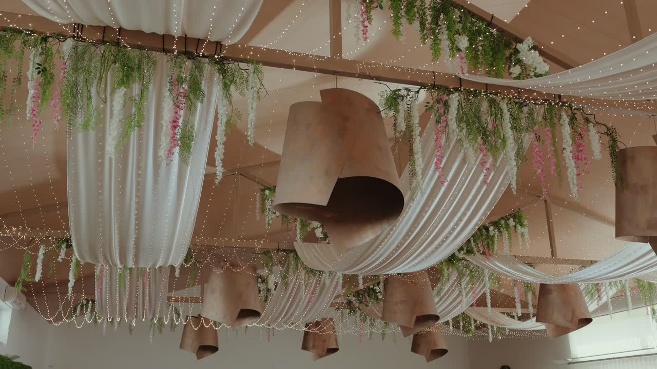 Beautiful ceiling adorned with fabric drapes, greenery, and hanging lamps for event decor