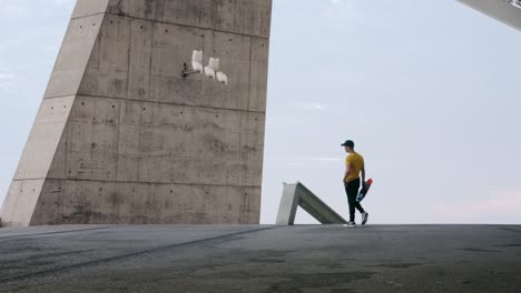 joven y atractivo hombre de moda patinando rápido bajo un panel solar en un día soleado por la mañana con un fondo urbano en cámara lenta