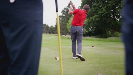 mature male golfer hitting tee shot along fairway with driver