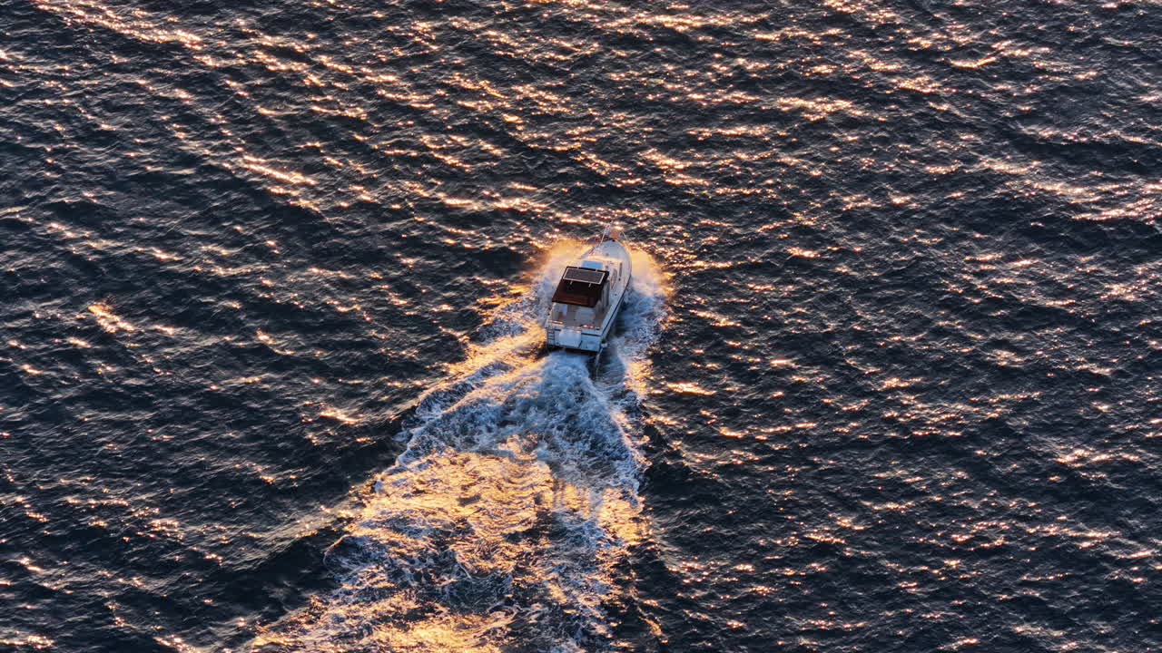Dronebillede i fugleperspektiv af en båd, der sejler ved solnedgang