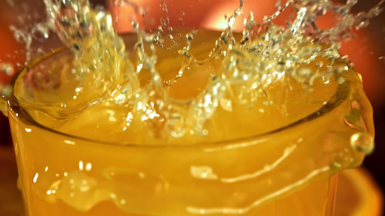 Succo d'arancia rinfrescante con cubetti di ghiaccio che schizzano al rallentatore