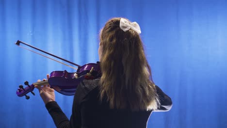 young woman playing violin on stage. music hall, opera.