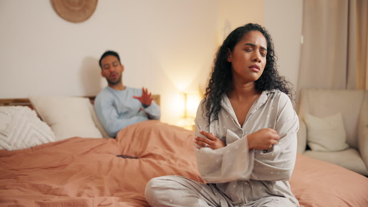 una pareja discutiendo en la cama.