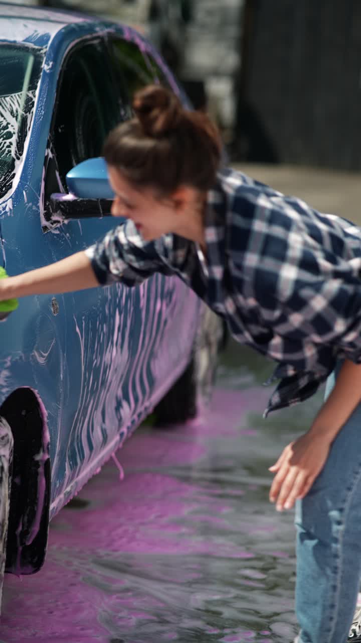 una mujer lavando un coche con gusto.