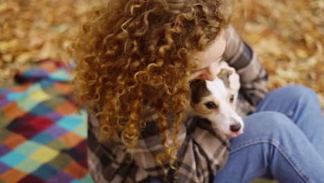 Curly-woman-hold-happy-jack-russell-terrier-puppy-and-pet-him-with-love