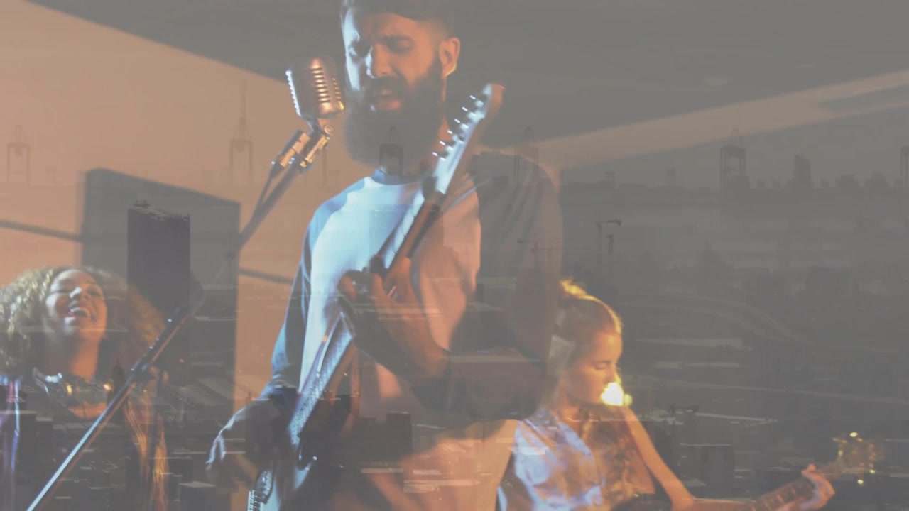 Vokalist går til mikrofonen etter at gitaristen starter en akkord, kamera zoomer inn på bybilde som overlegger musikk
