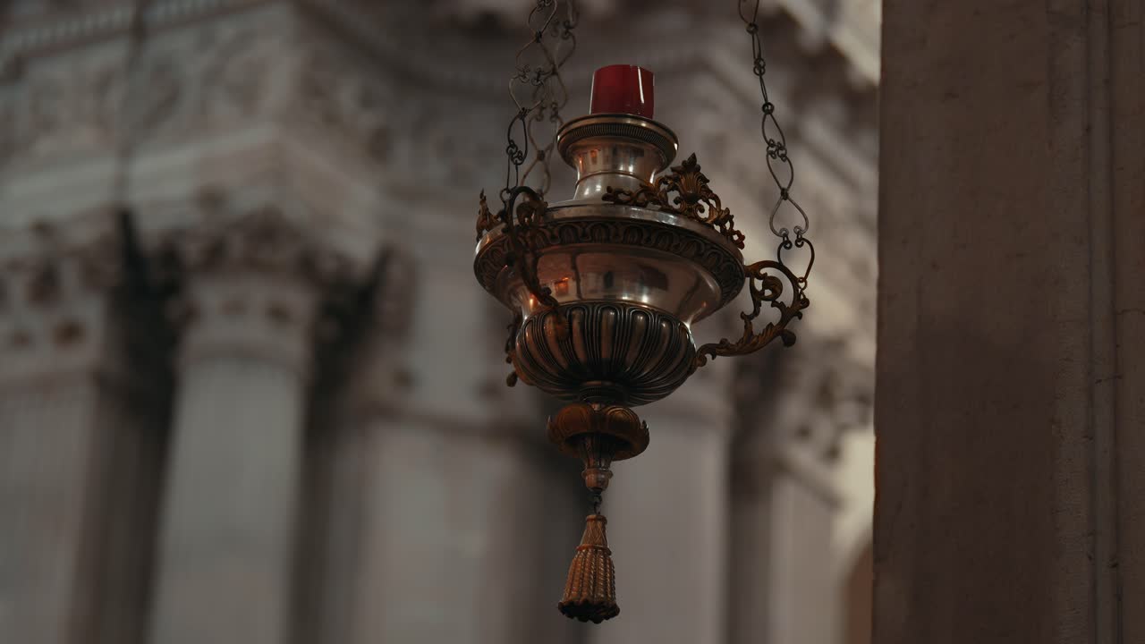 Ricercata lampada a sospensione dorata con decorazioni in metallo e sfondo sfocato dell'interno di una cattedrale, Brescia, lenta panoramica della telecamera