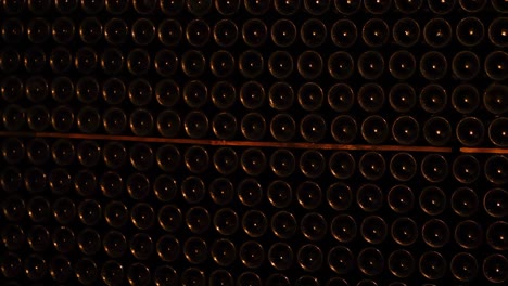 close-up view of stacked wine bottles in a dimly lit cellar, showcasing organized rows and dark ambiance.