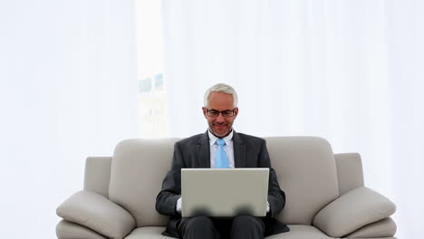successful businessman using laptop on the couch and cheering