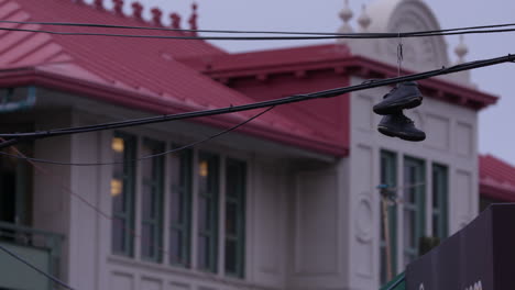 shoes, sneakers hanging on a telephone line in new york manhattan, in front of chinese style building