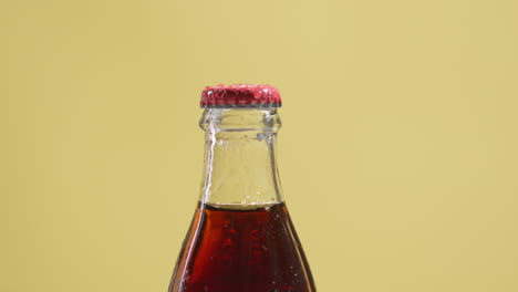 fotografía de cerca de una persona que pone una botella de cerveza fría o bebida gaseosa con tapa de metal y gotas de condensación