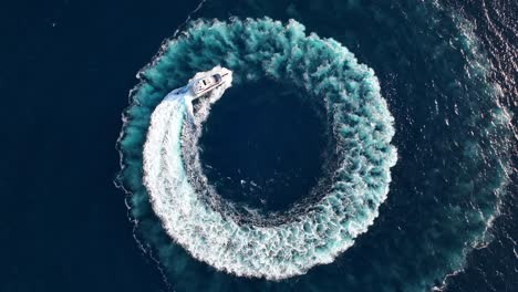 top down drone shot of luxury yacht driving in a circle at sea while zooming out