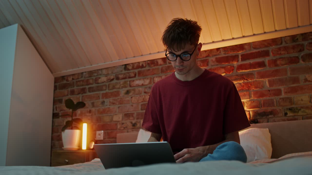 joven trabajando en una computadora portátil en su dormitorio