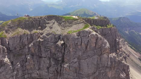 aerial footage of a mountain lodge perched on a rocky cliff in the dolomites, italy, showcasing dramatic landscapes and alpine scenery