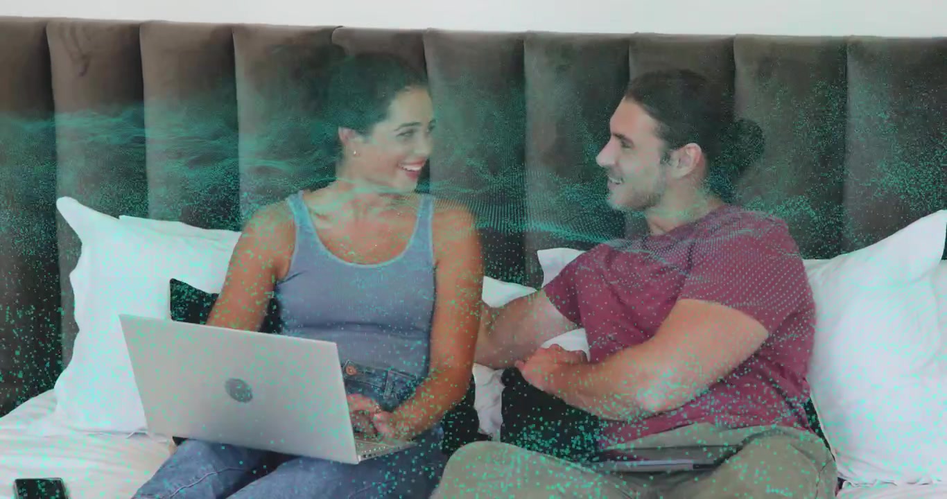 Pareja en la cama colocando una laptop y escribiendo juntos mientras uno de ellos señala, y una superposición turquesa pulsa