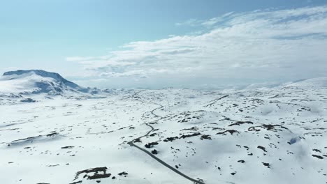 stunning view of road 55 crossing sognefjellet mountain pass between luster and lom in norway - springtime sunny aerial with snow left in landscape