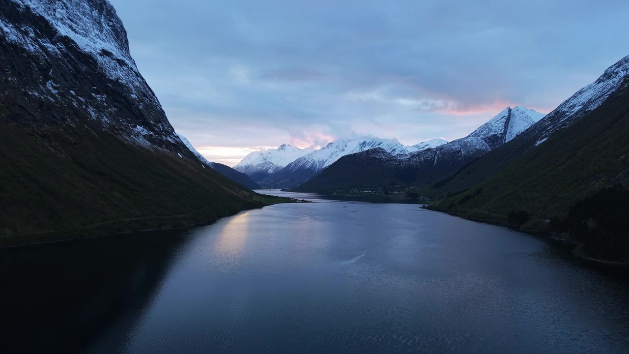 En rolig fjord med sneklædte tinder under en skumringsfarvet himmel. Ideel til rejse- og naturprojekter.