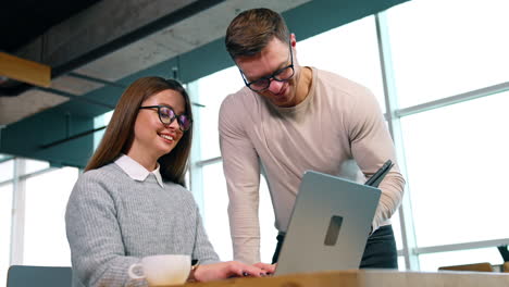 a pair of colleagues are in the office. male and female co-workers use gadgets and communicate together.