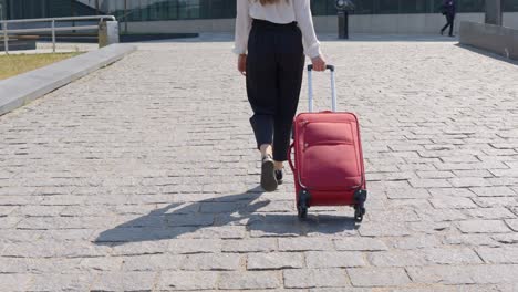 brunette businesswoman with red suitcase heading to office