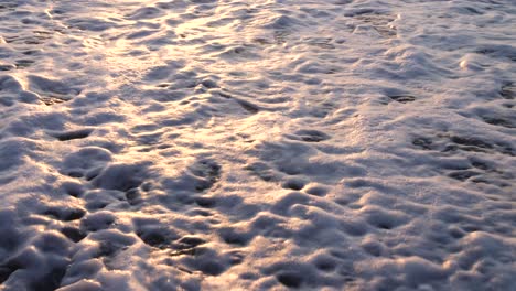 panning-of-waves-coming-onto-the-rocky-beach-at-sunset