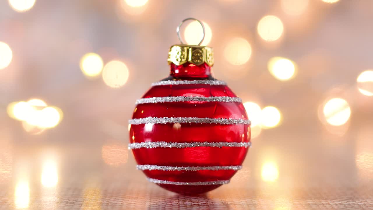 Primo piano di un ornamento natalizio rosso lucido con luci intermittenti sullo sfondo