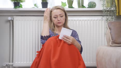 woman leaning on heater looking at high bill.