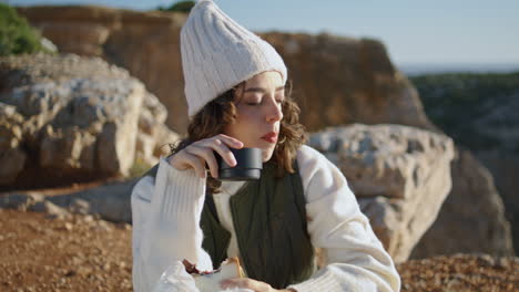 Travel-girl-enjoying-meal-at-rocky-mountain-vertical.-Calm-traveler-closing-eyes