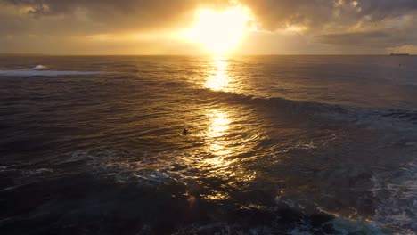 aerial drone pan shot of scenic morning sun rise with surfer waiting and riding wave central coast pacific ocean travel tourism nsw australia 4k