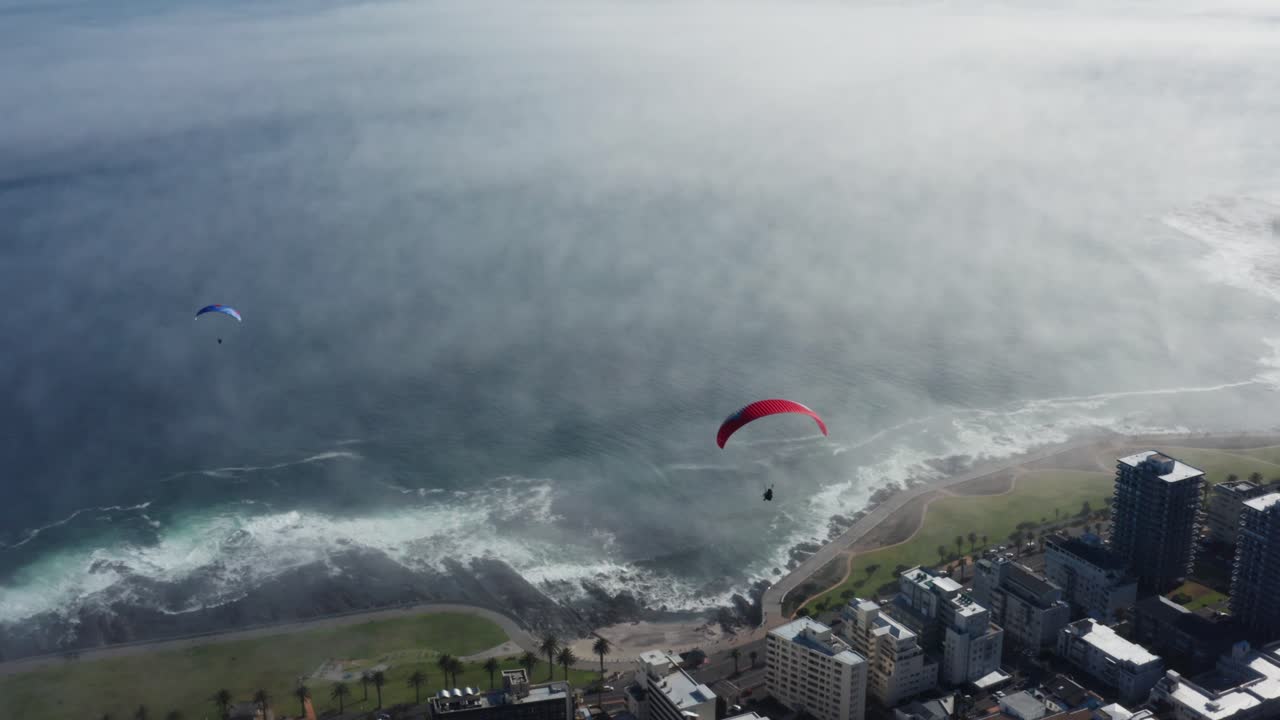 Paragliders fly over city and ocean in Cape Town, South Africa. Thrill and adventure concept.